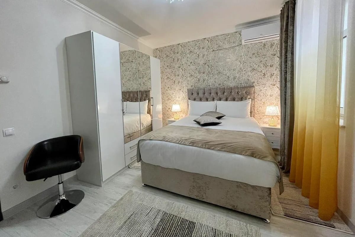 Een slaapkamer met een bed, nachtkastjes, een stoel en een spiegel.