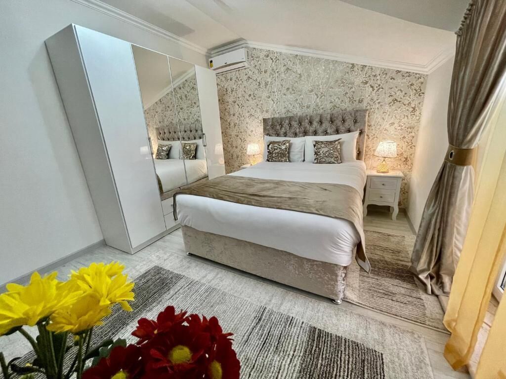 Un dormitorio con una cama grande, un armario, un espejo y una mesita de noche con una lámpara.