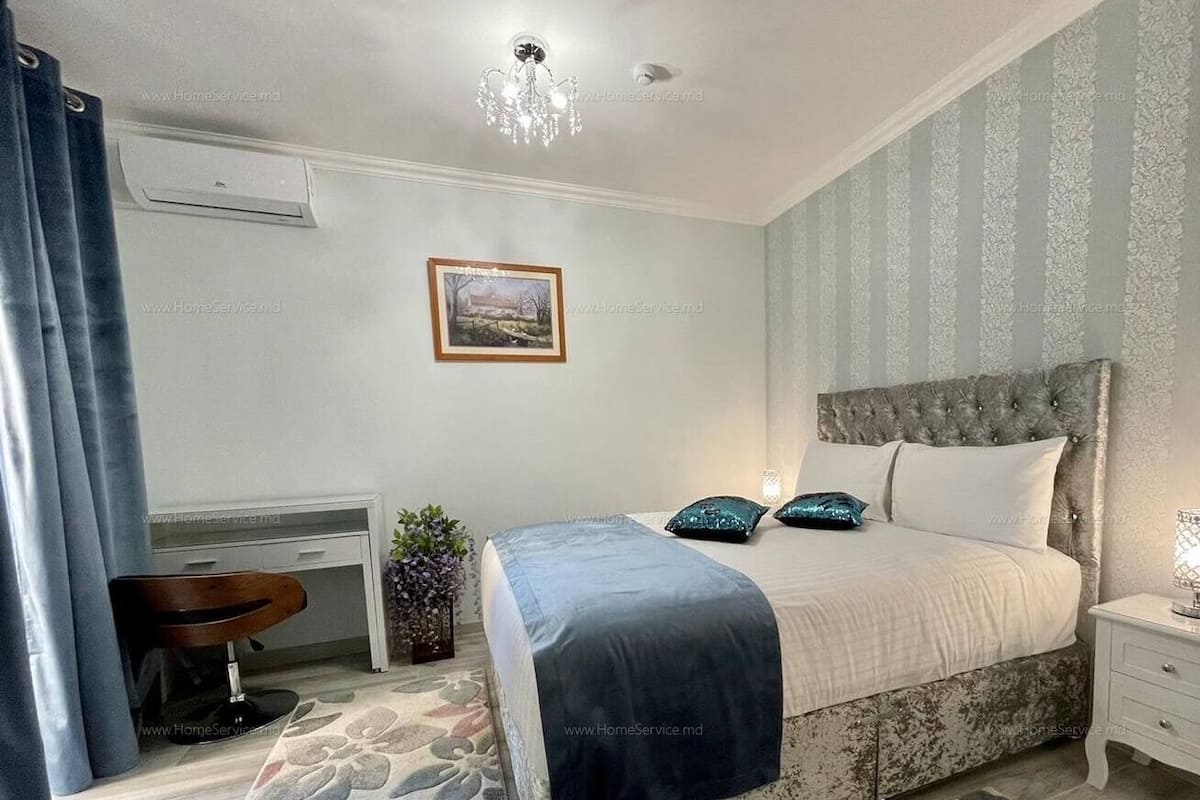 Een slaapkamer met een bed, nachtkastje, stoel en een klein bureau.