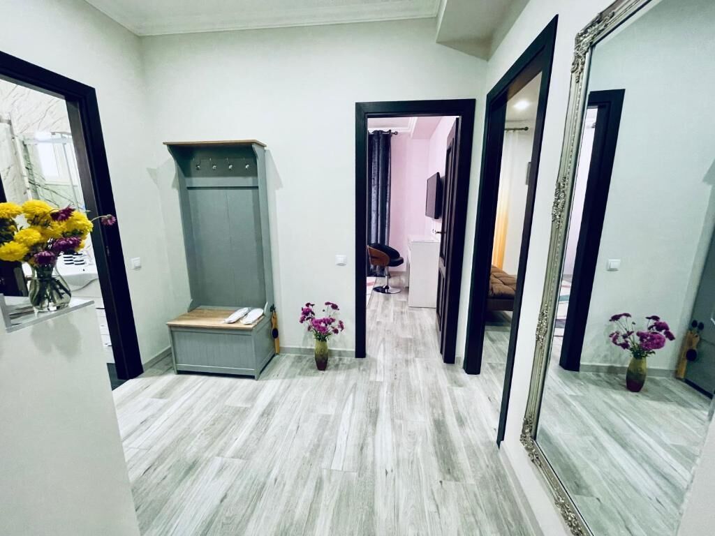 A hallway with a grey wardrobe, a mirror, and a vase with flowers.
