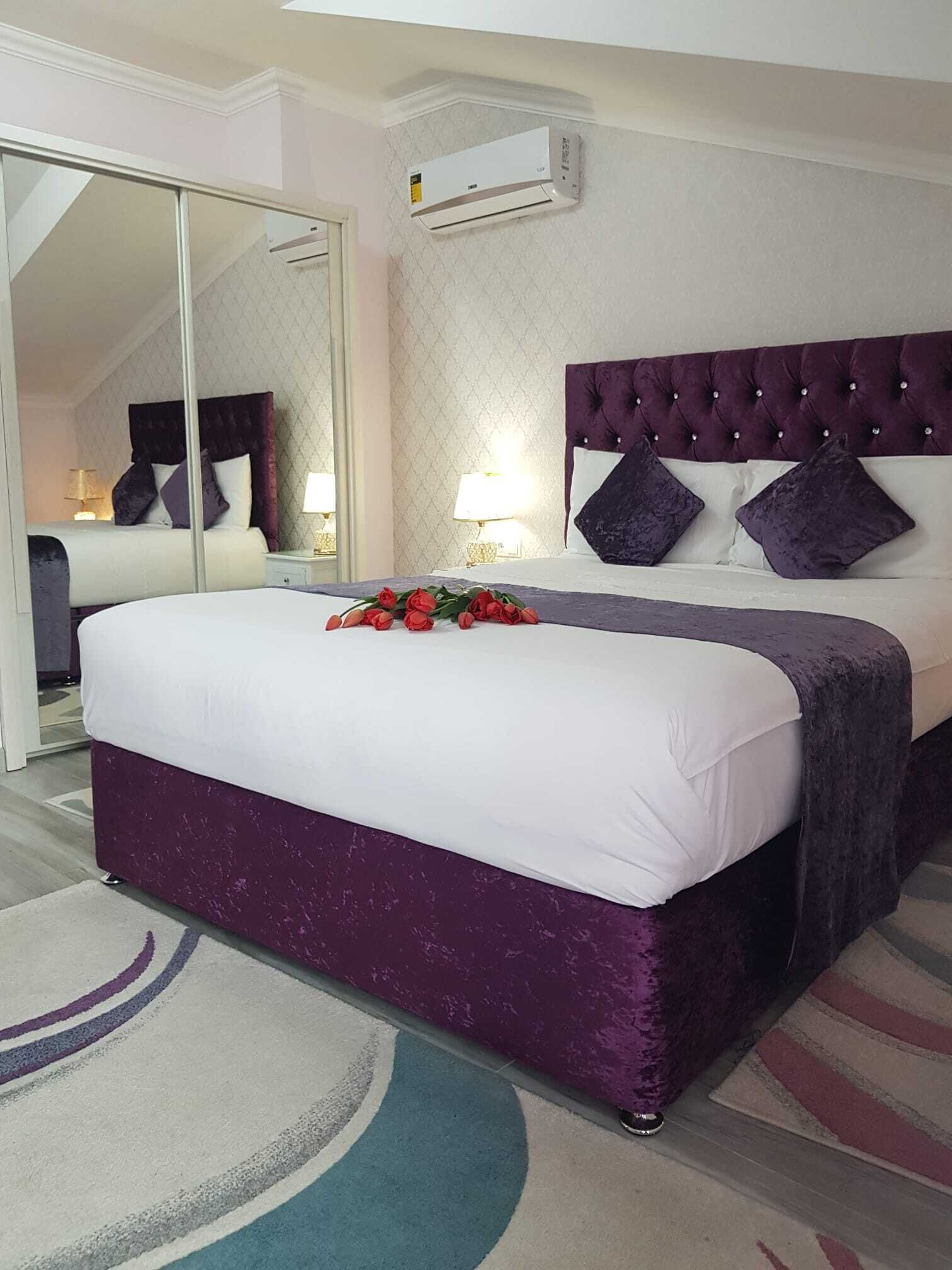 Habitación de hotel con una cama grande, un espejo, un equipo de aire acondicionado y piso alfombrado.
