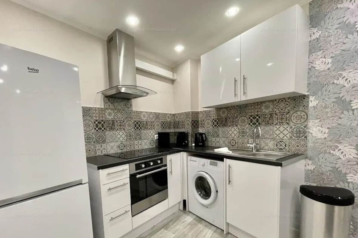 Een kleine keuken met een koelkast, oven, wasmachine en een spoelbak.