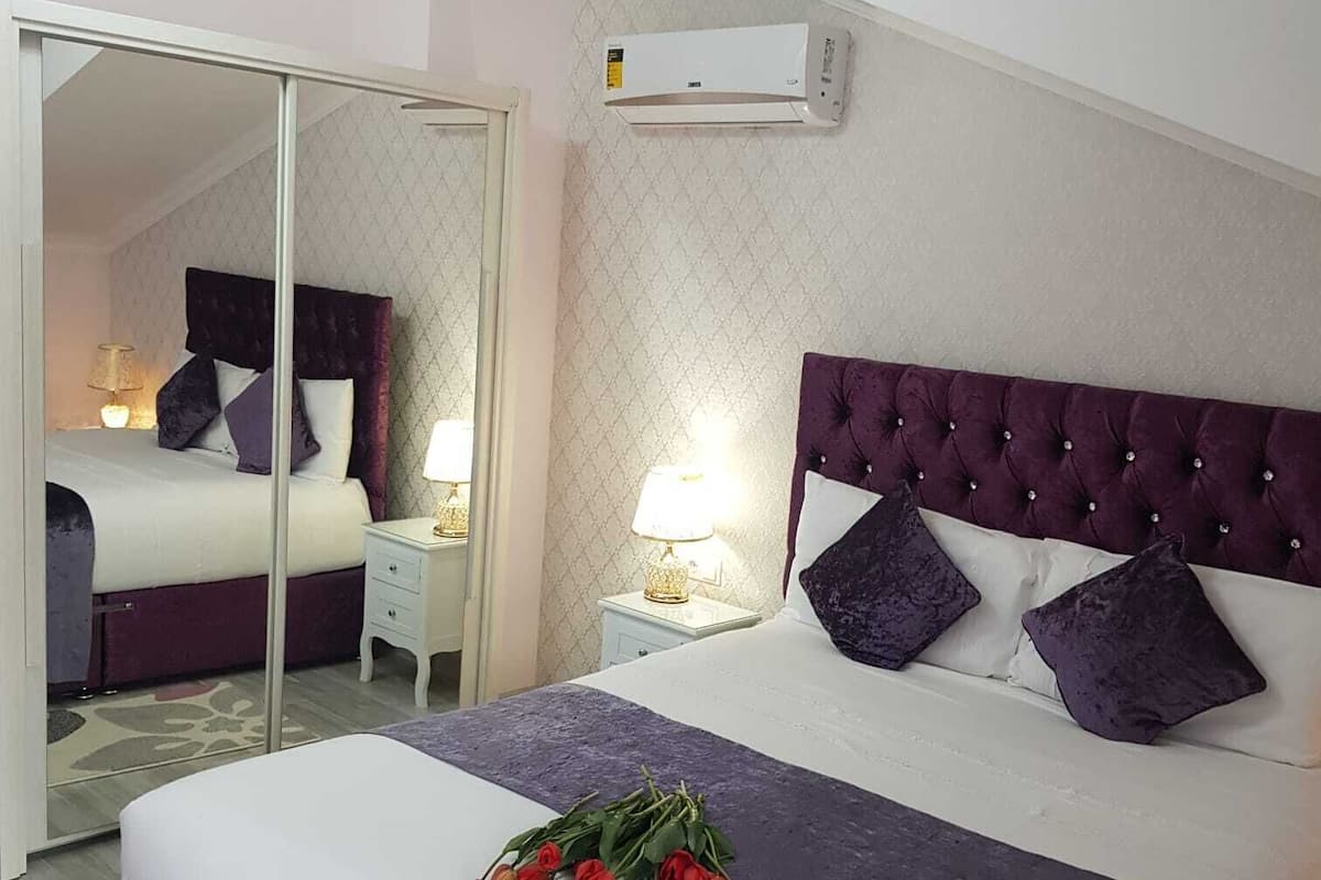 Een hotelkamer met een groot bed, een spiegel, een plafondventilator en een airconditioning.