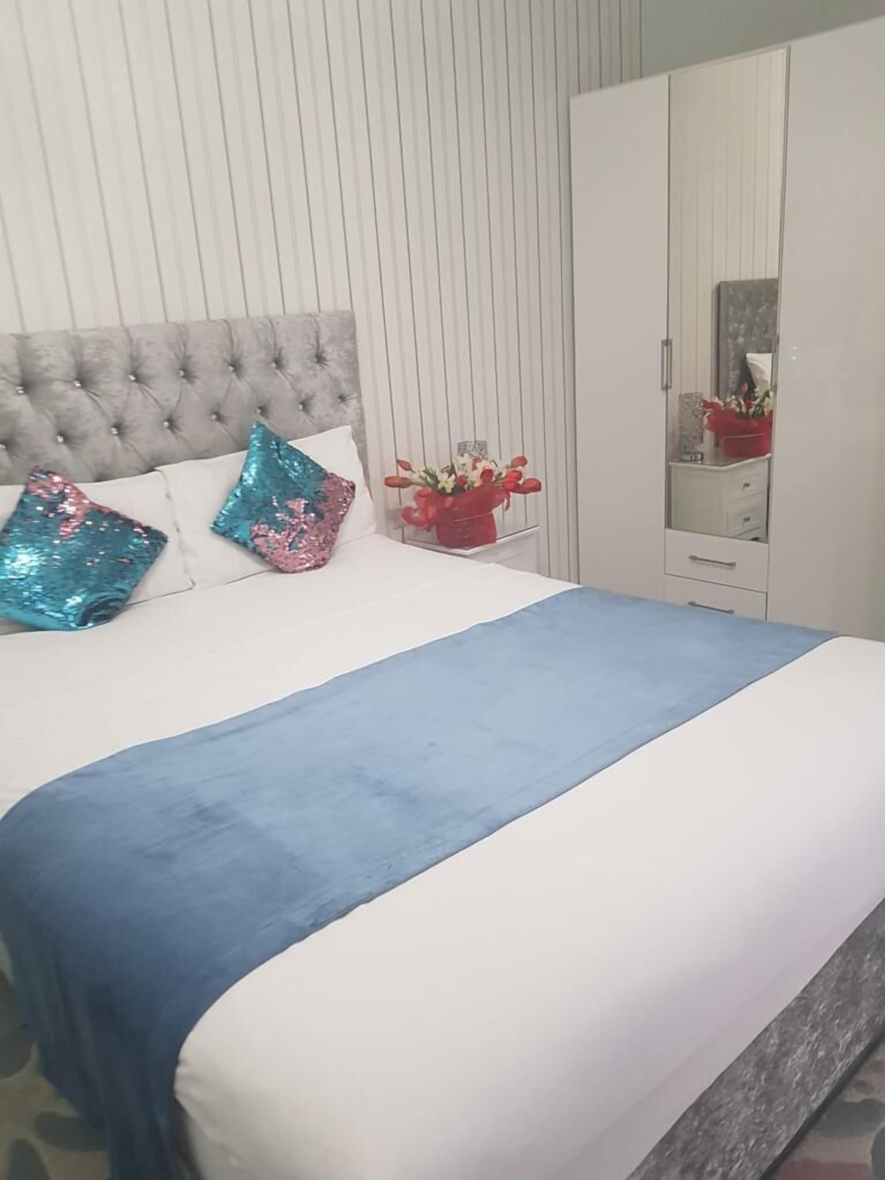 A bed with a tufted headboard, a blue bedspread, and decorative pillows.