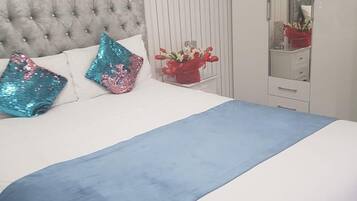 A bed with a tufted headboard, a blue bedspread, and decorative pillows.
