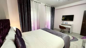 Un dormitorio con cama, escritorio, silla, televisor y candelabro.