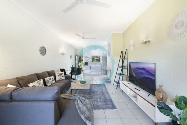 A modern living room with a sofa, TV, and a staircase leading to an upper floor.