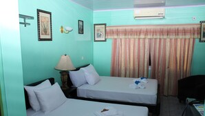 A room with two single beds, a desk, a chair, a lamp, and a window with curtains. - Quality Inn Suites, Guyana (Georgetown)