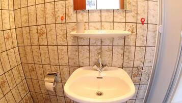 Un baño pequeño con inodoro, lavamanos y ducha.