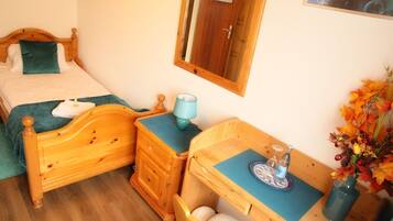 Un dormitorio con una cama de madera, una mesita de noche, un aparador y un escritorio con una silla.