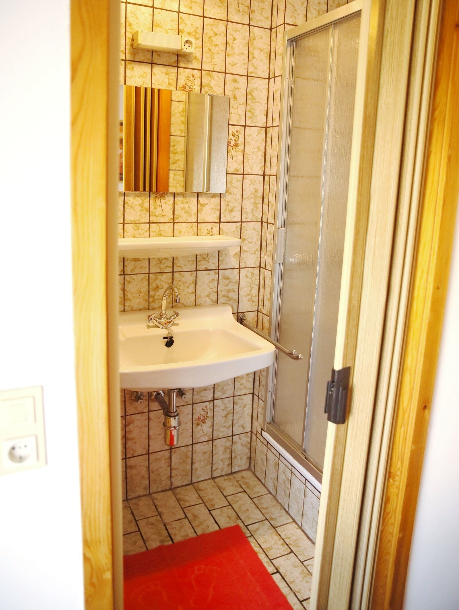 A bathroom with a white sink, mirror, and shower.