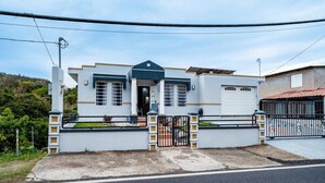 Uma casa de dois andares com portão da frente, garagem e um pequeno jardim.