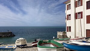 Un muelle con barcos amarrados y un edificio con contraventanas rojas.