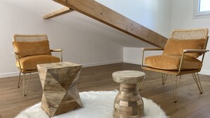 Una habitación tipo loft con dos sillas, una mesa de centro de madera y un taburete redondo de madera.