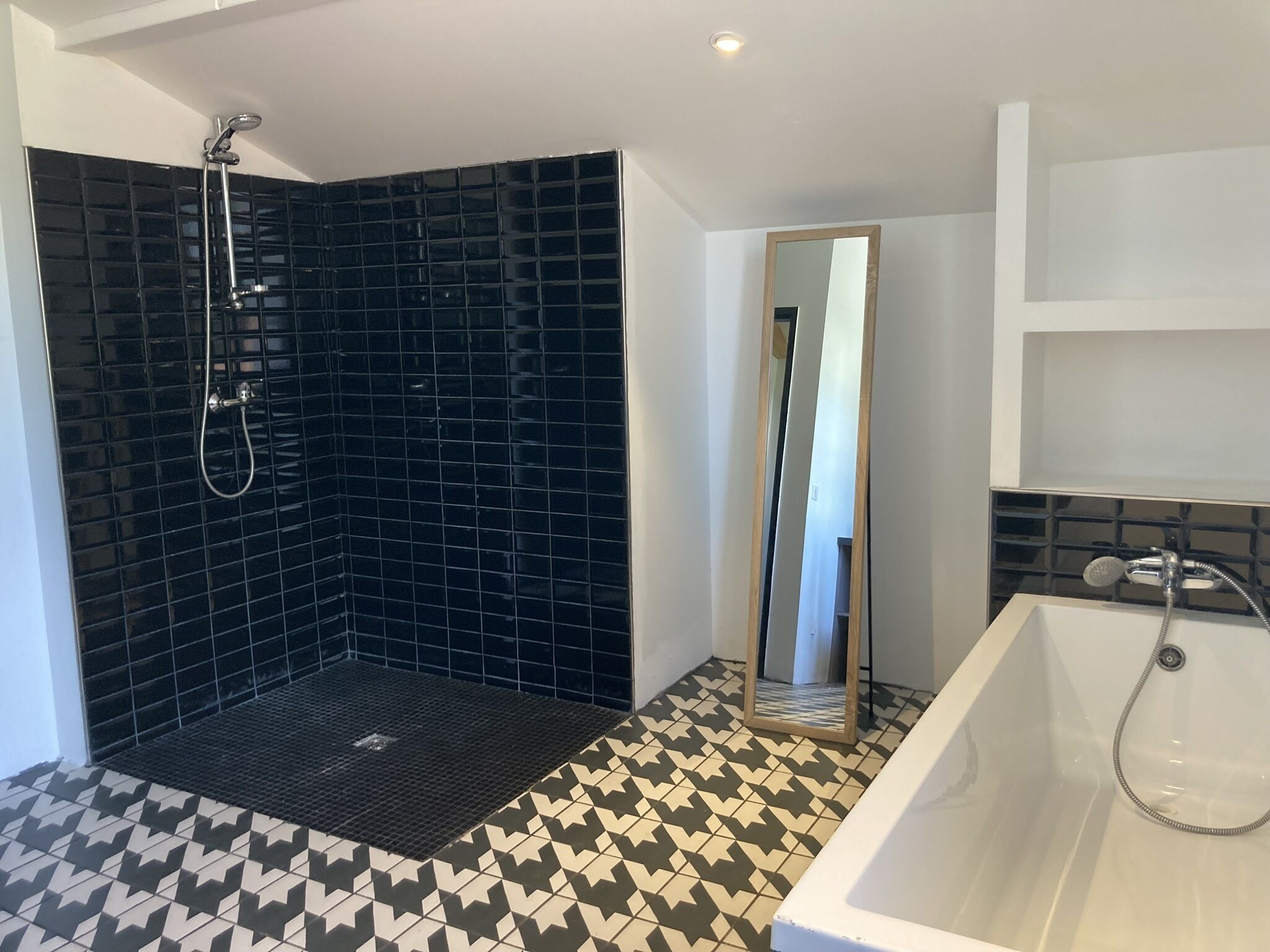 Une salle de bain avec une douche, une baignoire et un carrelage au sol.