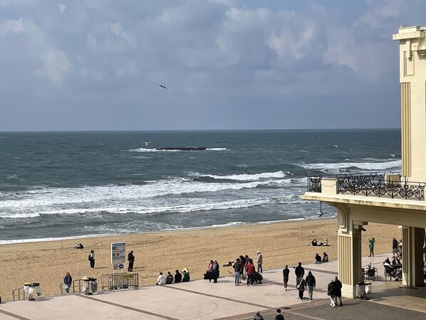 Una playa con gente, olas y un edificio con balcón.