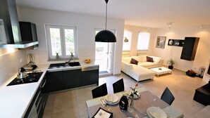 A modern kitchen with a dining area, white tiled walls, and a black ceiling light. - Villa Gea - Three Bedroom with Swimming Pool (Barban)