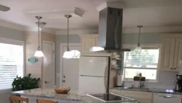 A modern kitchen with a central island, pendant lighting, and a built-in stove. - Your Happy Place (Melbourne)