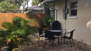 A patio with a table and chairs, a potted plant, and a brick floor. - Your Happy Place (Melbourne)