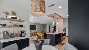 A modern kitchen with a dining area, featuring a round table, chairs, and a hanging light fixture. - 3BR Boho Design | Fire Pit | Steps to Beach (North Myrtle Beach)