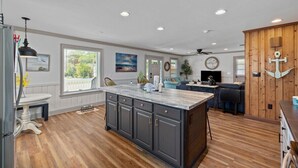 A spacious kitchen with a large island, wooden flooring, and a dining area with a white table and chairs.