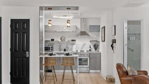 A modern kitchen with white cabinets, a central island, and two bar stools.