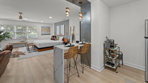 A modern living space with a bed, seating area, dining table, and kitchen area.