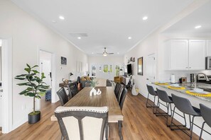 Una cocina moderna con armarios blancos, una mesa de comedor de madera y una barra.
