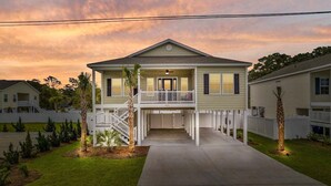 A two-story house with a front porch, a covered entryway, and a small front yard. - Landing Zone | Pet-Friendly 4BR w/ Pool + Hot Tub (North Myrtle Beach)