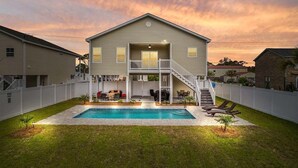 A two-story house with a front deck, a swimming pool, and a staircase leading to the deck. - Landing Zone | Pet-Friendly 4BR w/ Pool + Hot Tub (North Myrtle Beach)