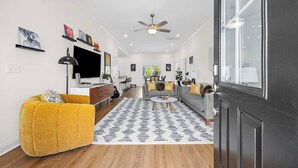 A modern living room with a sofa, coffee table, and a ceiling fan. - Landing Zone | Pet-Friendly 4BR w/ Pool + Hot Tub (North Myrtle Beach)
