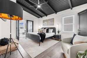 A modern bedroom with a bed, a desk, a chair, and a large window.