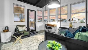 Un salon moderne avec un canapé, une table à manger et une grande fenêtre donnant sur des maisons.