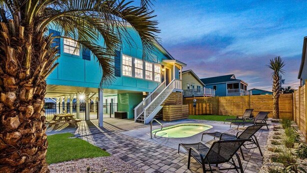 A backyard with a swimming pool, lounge chairs, and a wooden deck. - Hem's Hideout | 5BR Tropical Oasis w/ Heated Pool (North Myrtle Beach)