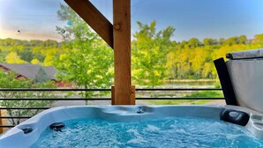 Ein Whirlpool mit einer Holzterrasse und Blick auf eine grüne Landschaft.