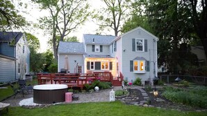 A two-story house with a deck, hot tub, and garden.
