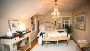A bedroom with a large bed, a desk, and a chandelier.