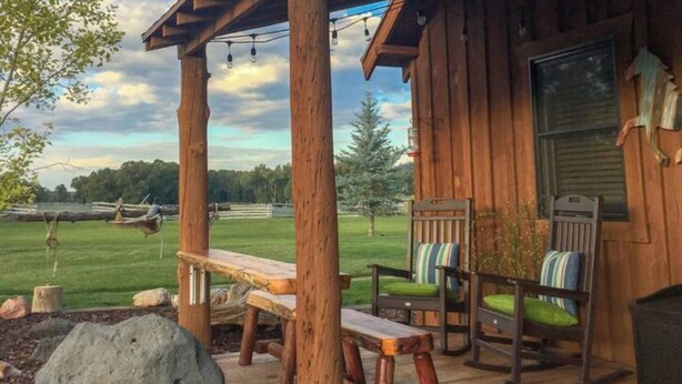 A wooden cabin with a porch, a bench, two rocking chairs, and a view of a grassy field. - Utah's Best-Kept Secret: Secluded and Serene Cabin Getaway, Uta's Best-Kept Secret: Secluded and Ser (Garfield County)