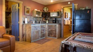 A compact kitchen with a central island, wooden cabinets, a refrigerator, and a dining area with a table. - Utah's Best-Kept Secret: Secluded and Serene Cabin Getaway, Uta's Best-Kept Secret: Secluded and Ser (Garfield County)