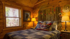 A cozy wooden room with a large bed, two bedside lamps, a window with blinds, and a framed picture on the wall. - Utah's Best-Kept Secret: Secluded and Serene Cabin Getaway, Uta's Best-Kept Secret: Secluded and Ser (Garfield County)