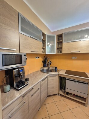A modern kitchen with built-in appliances, wooden cabinets, and a dishwasher. - Romantic cozy flat in the city center (Budapest)