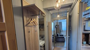 Un couloir avec une armoire en bois, un portant et un sol carrelé.