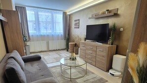 Un salon moderne avec un canapé, une table basse en verre, un téléviseur et un meuble en bois.