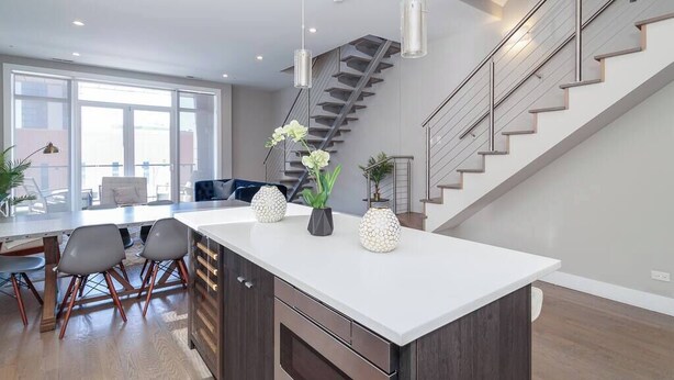 A modern kitchen with a central island, wooden cabinets, and a staircase leading to an upper level. - 2 Newly Built Luxury Condos with Private Roofdeck! (Chicago)