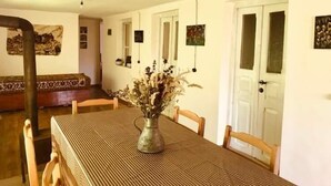 A dining area with a table set for four, a vase with dried flowers, and a bench in the background. - Lileo (Akhmeta)