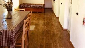 A dining area with a wooden table and chairs, a bench, and a wall with framed pictures. - Lileo (Akhmeta)