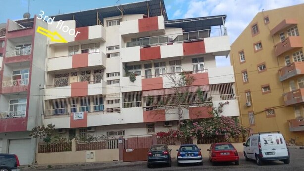 A multi-story residential building with balconies and a gated entrance. - Cubico Tota (Praia)