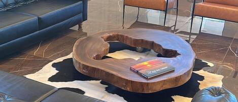 A modern lounge area with leather sofas, a wooden coffee table, and a glass partition.