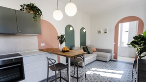 Una cocina moderna con horno empotrado, una mesa de comedor con sillas y un sofá en la zona de estar contigua.