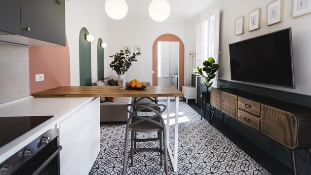 Una cocina moderna con una isla central, un televisor grande y una zona de comedor con banco.